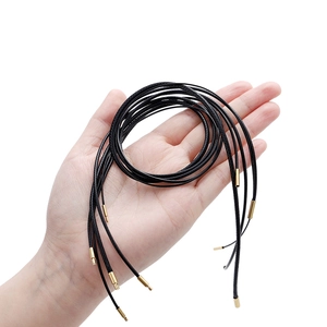 Vista detallada de cordones negros trenzados para collares con terminales de metal dorado