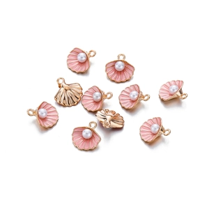 Detailopname van 10 gouden schelphangers met roze emaille en parelaccenten