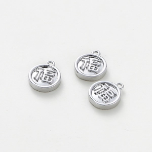 Detailed macro view of three silver Fu character charms with relief engraving for DIY jewelry