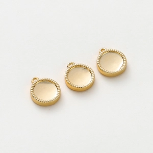 Detailed macro view of 18K gold-plated round pendant charms with ridged edges for DIY jewelry