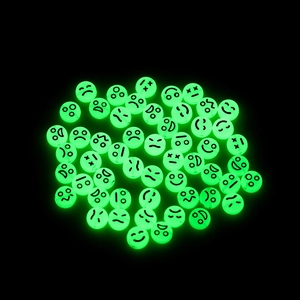 Dettaglio di perline rotonde in acrilico fosforescenti con varie espressioni emoji