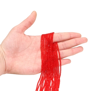 Détail de perles de cristal rouge à facettes de 2mm tenues en main pour bijoux DIY