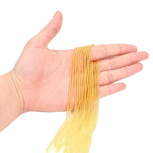 Détail de perles en cristal facetté jaune de 2mm tenues à la main pour bijoux DIY