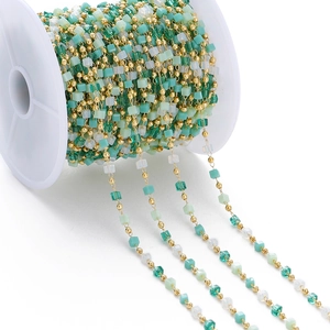 DIY jewelry chain with green crystal cube beads and gold metal links on a spool