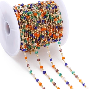 Macro shot of colorful transparent square beads and gold round beads on white spool