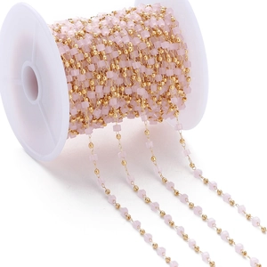 Close-up of pink translucent crystal cubes and gold beads on a DIY craft jewelry chain
