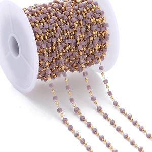 Macro detail of handmade beaded chain with gold round beads and purple square resin beads