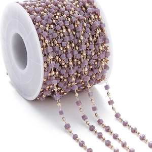 Detail view of purple matte cube beads and gold metal round beads on a large white spool