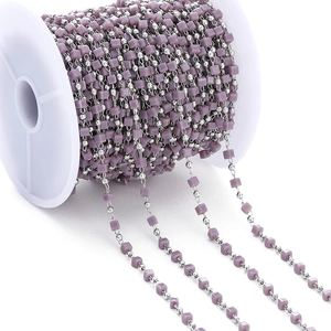 Detailed view of purple resin cube beads and silver metal beads on a white spool