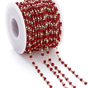 Detailed view of burgundy square beads and gold round beads on spool for DIY jewelry