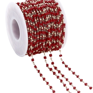 Handmade DIY accessory chain with red cube beads and gold round beads on a white spool