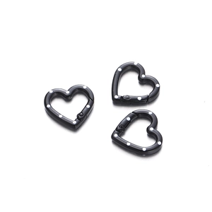 Detail of three heart-shaped black metal carabiners with white polka dots for DIY jewelry