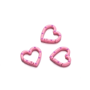 Close-up of pink heart-shaped spring ring buckles with purple polka dots for DIY jewelry