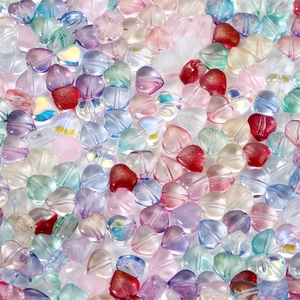 Close-up of colorful heart-shaped glass beads with matte and glitter finishes for DIY jewelry