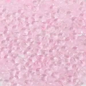 Macro shot of pink heart-shaped glass beads with central drill holes for jewelry making