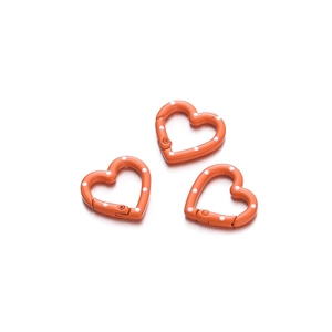 Detailed view of three orange heart-shaped carabiners with white polka dot patterns