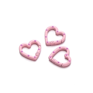 Detailed close-up of pink heart-shaped spring buckles with purple polka dots for DIY jewelry