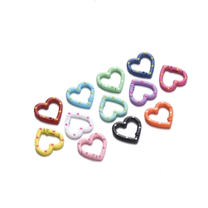 Macro shot of 12 colorful heart-shaped metal spring rings with polka dot enamel patterns