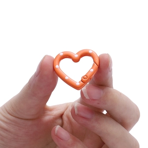 Detail of 24mm orange heart spring clasp with white polka dots held by hand