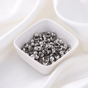 Gros plan de perles d'arrêt en acier inoxydable 6mm sur fond de soie blanche soyeuse