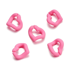 Macro detail of five bright pink lip-shaped silicone DIY jewelry connectors on white