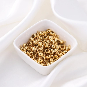 Perles d'espacement de 6mm en acier doré avec boucle présentées dans un bol en porcelaine