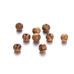 Macro detail of natural maple wood beads with dark stripes and pre-drilled holes for DIY