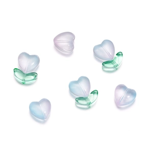 Dettaglio macro di perle in vetro a forma di cuore e foglia per accessori per gioielli fai-da-te