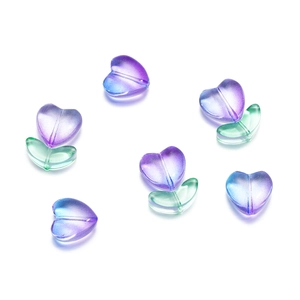 Dettaglio macro di perline a tulipano in vetro sfumato viola e foglie verdi per gioielli