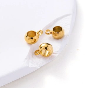 Vue détaillée de trois perles creuses en acier inoxydable doré de 6mm avec boucles