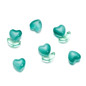 Dettaglio di perline in vetro satinato verde menta a forma di cuore e foglia per gioielli
