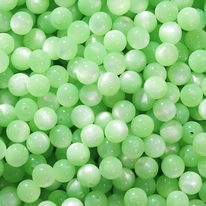 Macro view of light green resin beads with cat eye luster for DIY jewelry making