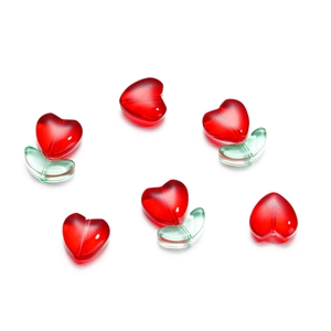 Dettaglio di perline a cuore in vetro rosso con foglie verdi per gioielli fai-da-te