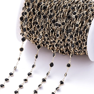 Detail van gouden ketting met zwarte gezette zirkoonstenen op een witte spoel