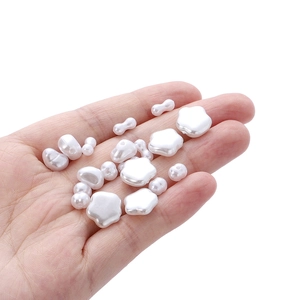 Varie perle barocche in ABS bianco per creazione di gioielli fai da te mostrate in mano