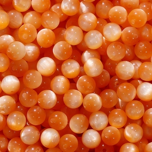 Macro shot of orange cat eye resin beads with silky luster for DIY jewelry making