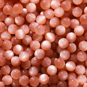 Macro detail of round light pink resin beads with cat-eye effect for jewelry making