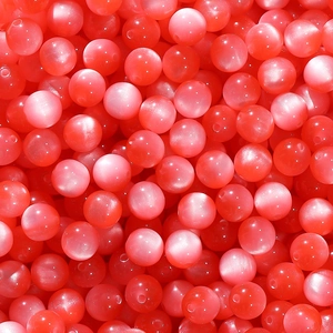 Detailed macro view of watermelon red resin beads featuring a glossy cat-eye optical effect
