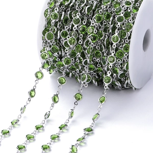 Detailopname van een zilveren koperen ketting met groene zirkoon op een witte spoel