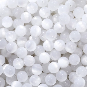 Macro shot of milky white resin cat-eye beads with smooth silk luster and center holes