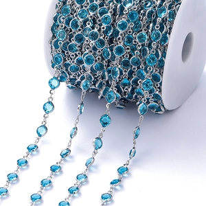 Detailopname van de verzilverde ketting met blauwe zirkoonstenen op een witte spoel