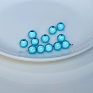 Close-up of bright blue laser luster round loose beads on a silver pin for jewelry DIY