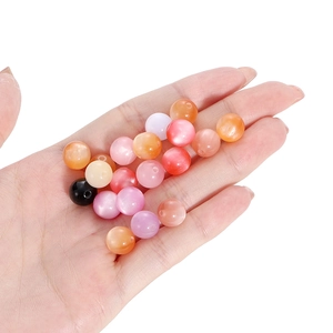 Mix of colorful cat eye resin round beads held in hand for DIY jewelry making material