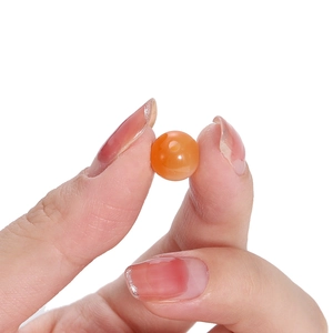 Polished orange resin cat-eye round bead held in hand for DIY jewelry making material