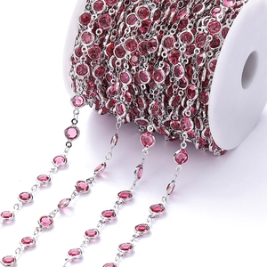 Macro-opname van verzilverde DIY-sieradenketting met gefacetteerde roze zirkoon op een rol
