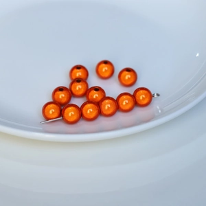 Macro detail of reflective orange laser pearlescent beads for DIY jewelry and phone chains
