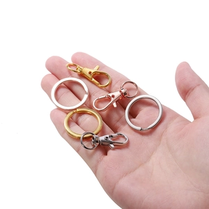 Hand hält Metall-Karabinerverschlüsse und flache Schlüsselringe für DIY-Schmucksets