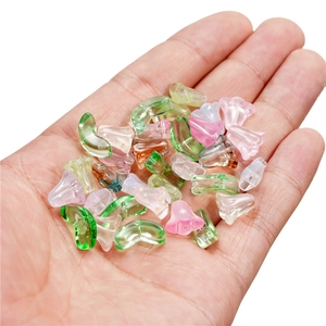 Colorful translucent glass trumpet flower and leaf beads held in hand for DIY jewelry