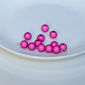 Vista macro di perle acriliche rosa fucsia con riflessi metallici per gioielli fai-da-te