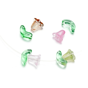 Close-up of translucent glass lily flower beads and green leaf charms for DIY jewelry